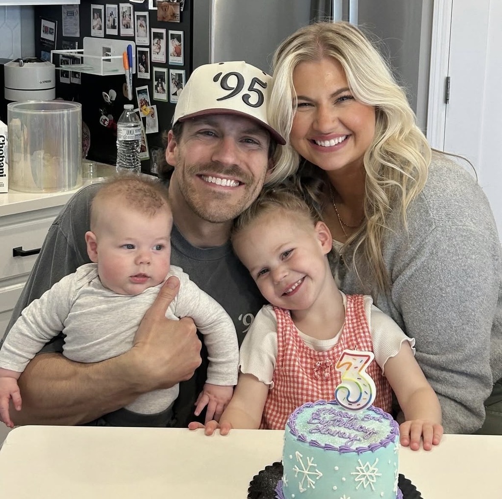 family of four sitting at their kitchen table with a birthday cake in front of them