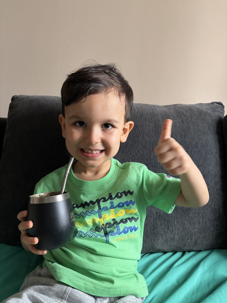 young boy holding a cup and giving a thumbs up