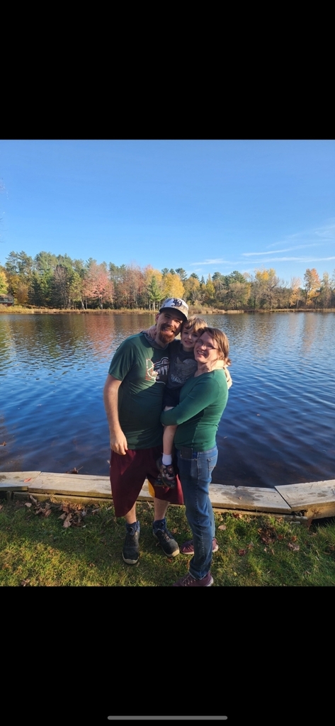 two parents and a young boy standing next to a lake