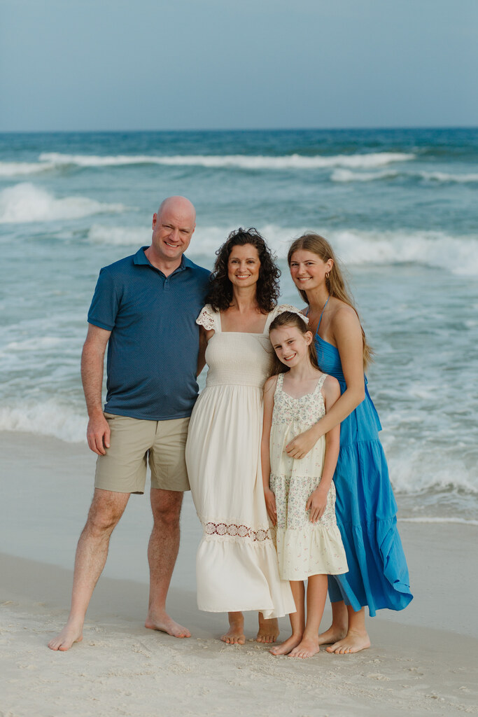 family standing on a beach by the ocean