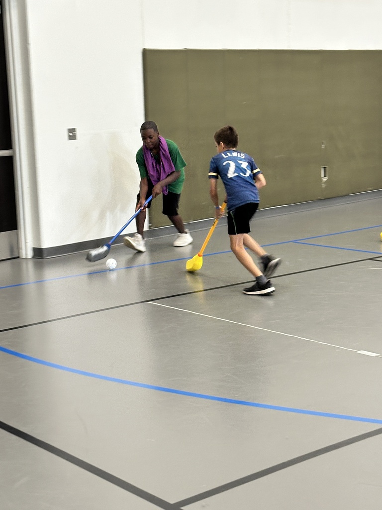 kids playing floor hockey in a gym