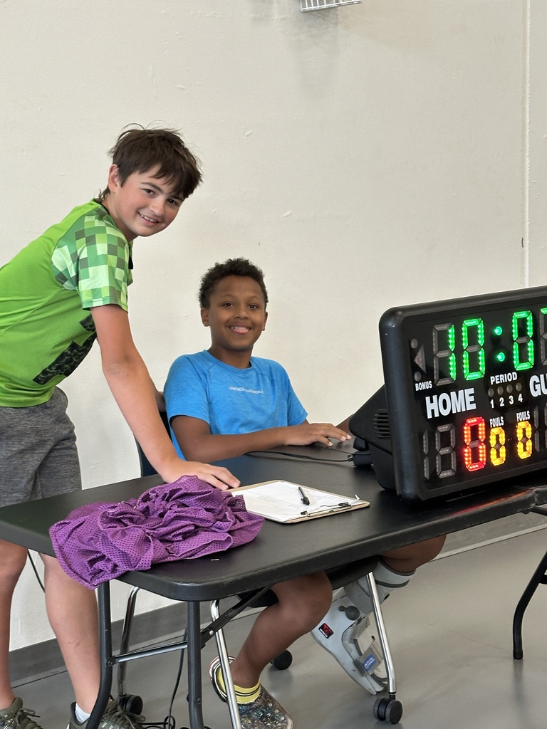 two boys sitting at a score table during a basketball game
