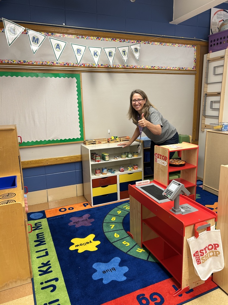 woman setting up a hands-on play area of a kindergarten classroom