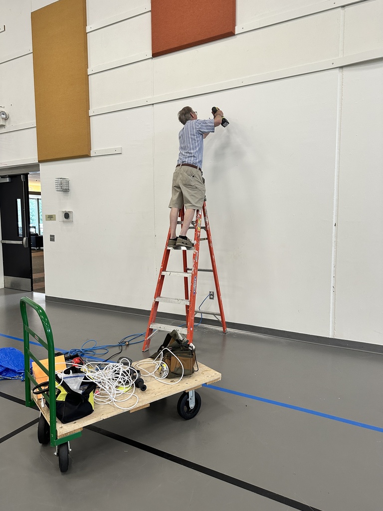teacher on a ladder installing a new intercom system