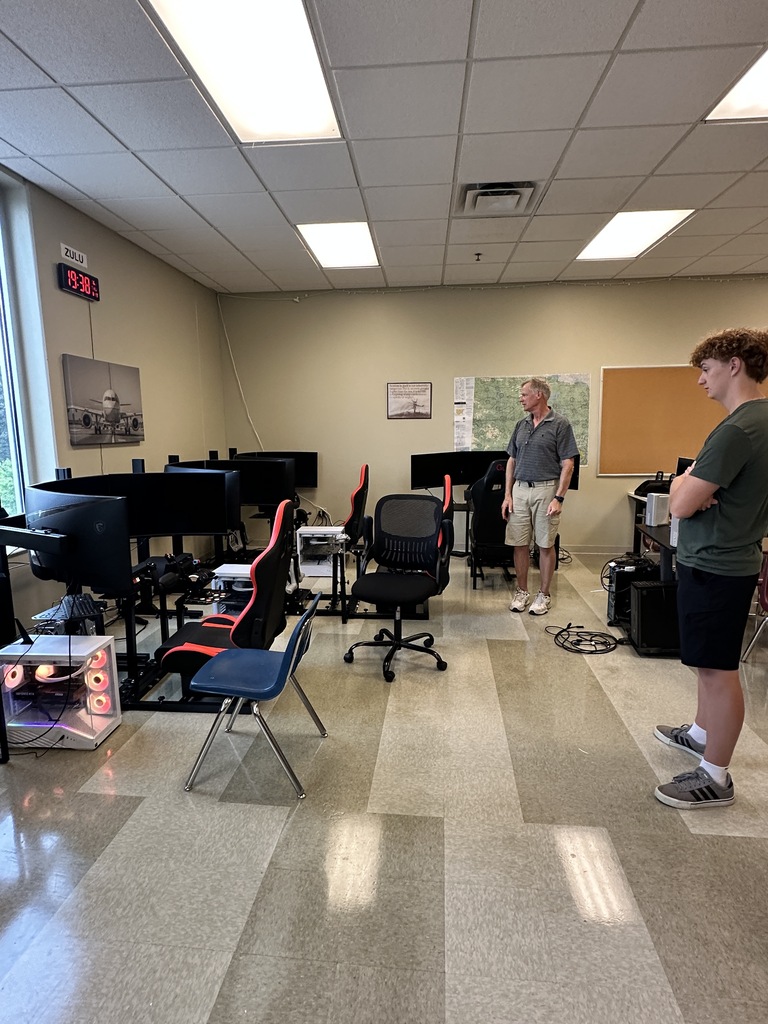 teacher and student looking at flight simulators