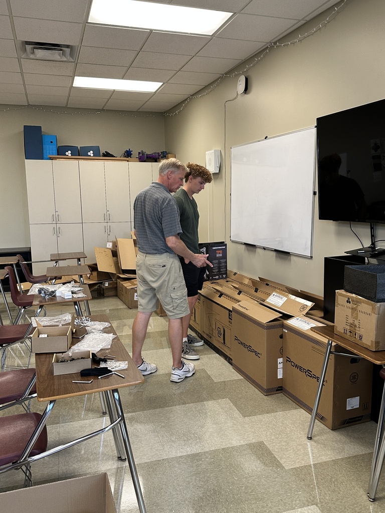 teacher and student looking at boxes for the new flight simulators