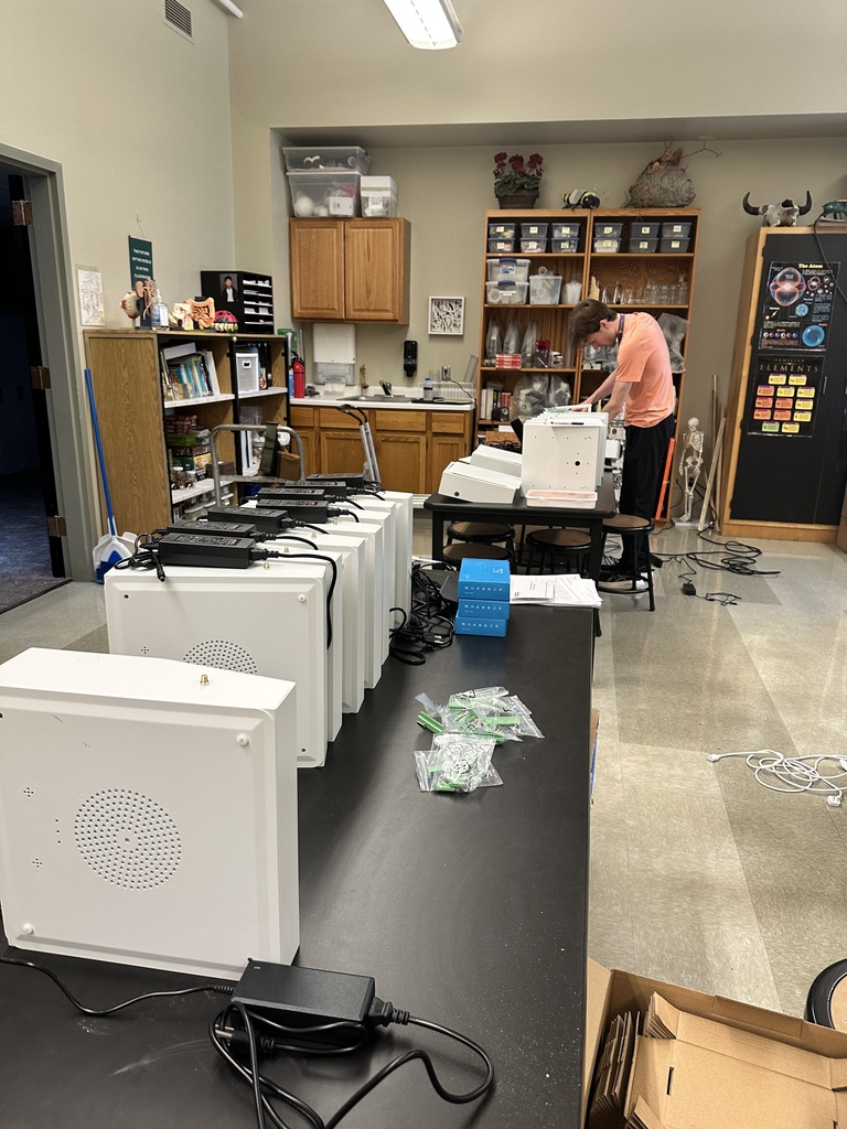 teacher standing next to a table with a row of new technology devices