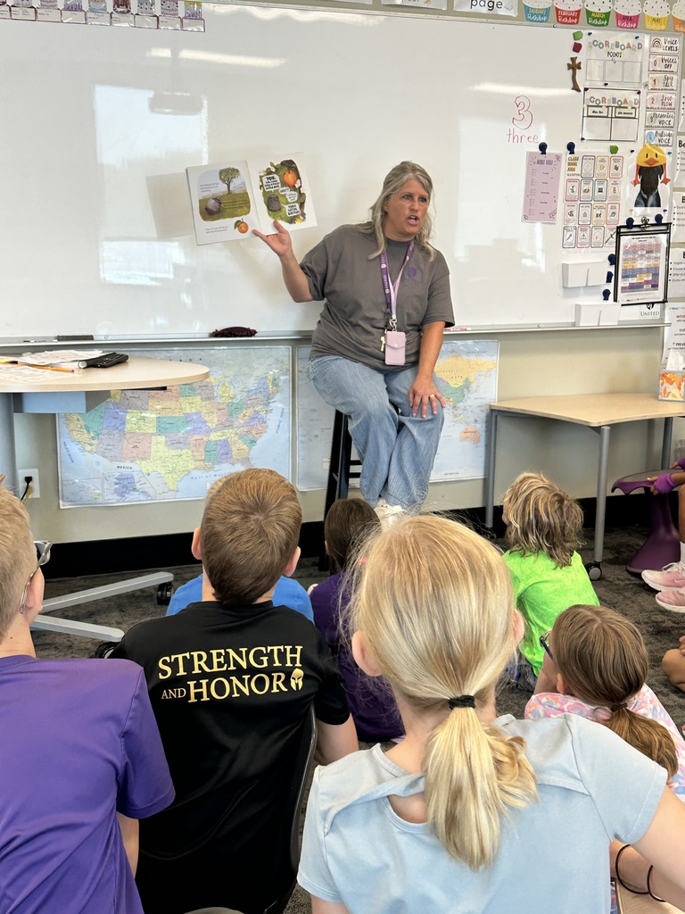 teacher in front of the classroom reading a book