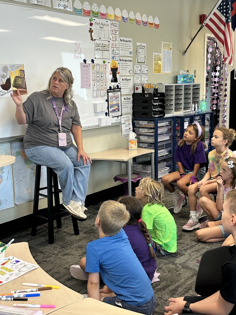 teacher in front of the classroom reading a book