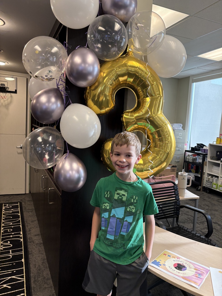 student standing by some balloons