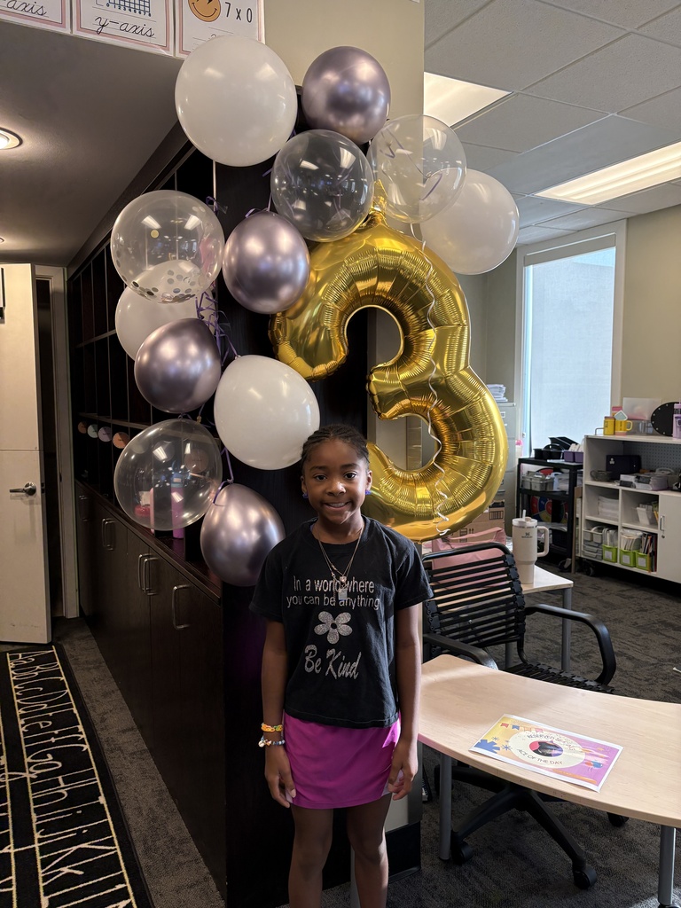 student standing by some balloons