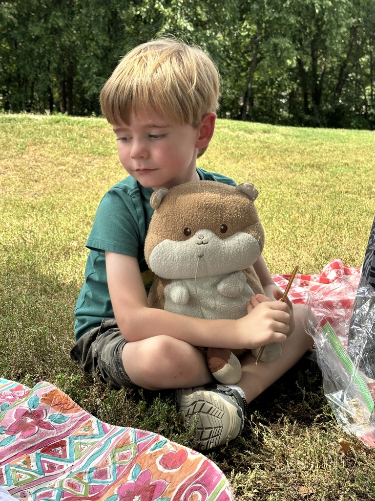 student sitting outside with a stuffed animal in his lap