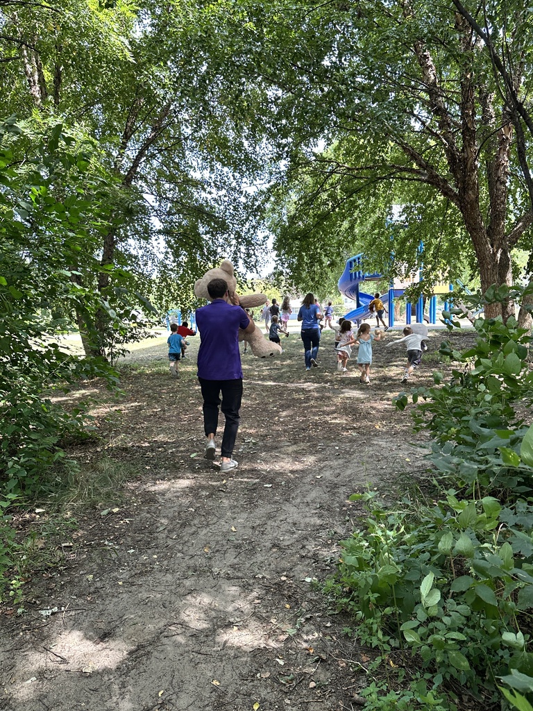 teacher holding a big teddy bear running with students