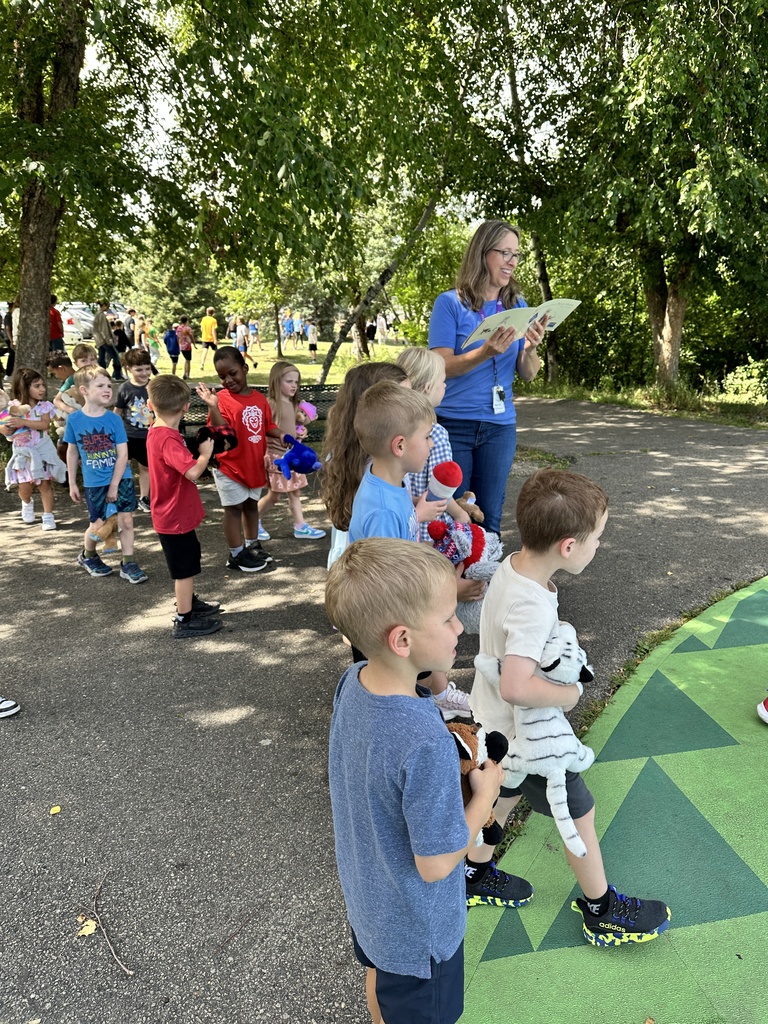 teacher with kindergarten students reading a book outside
