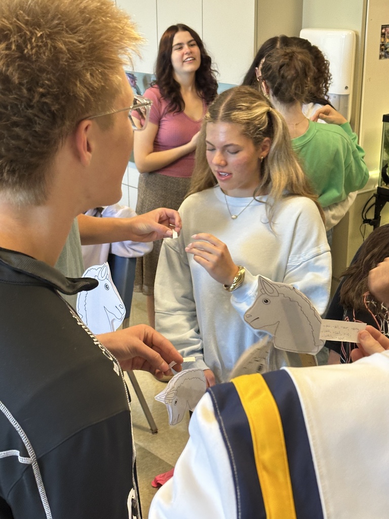 high school students in a classroom holding stick horses and pieces of paper