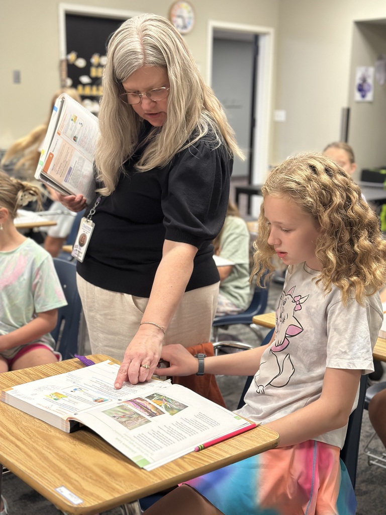 teacher walking around classroom helping students at their desk