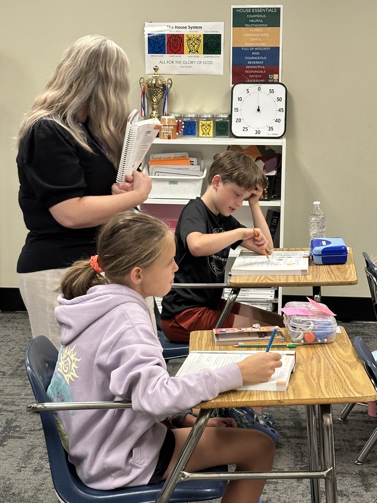 teacher walking around classroom helping students at their desk