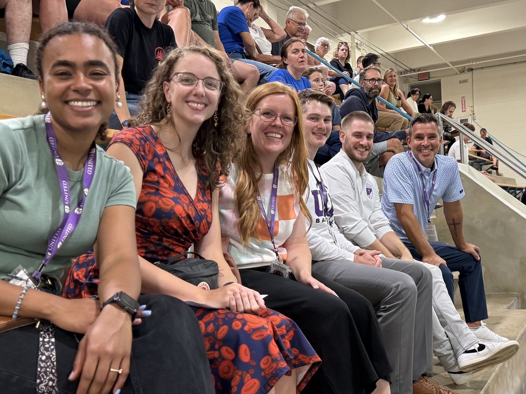 row of teachers sitting in the bleachers at a swim meet