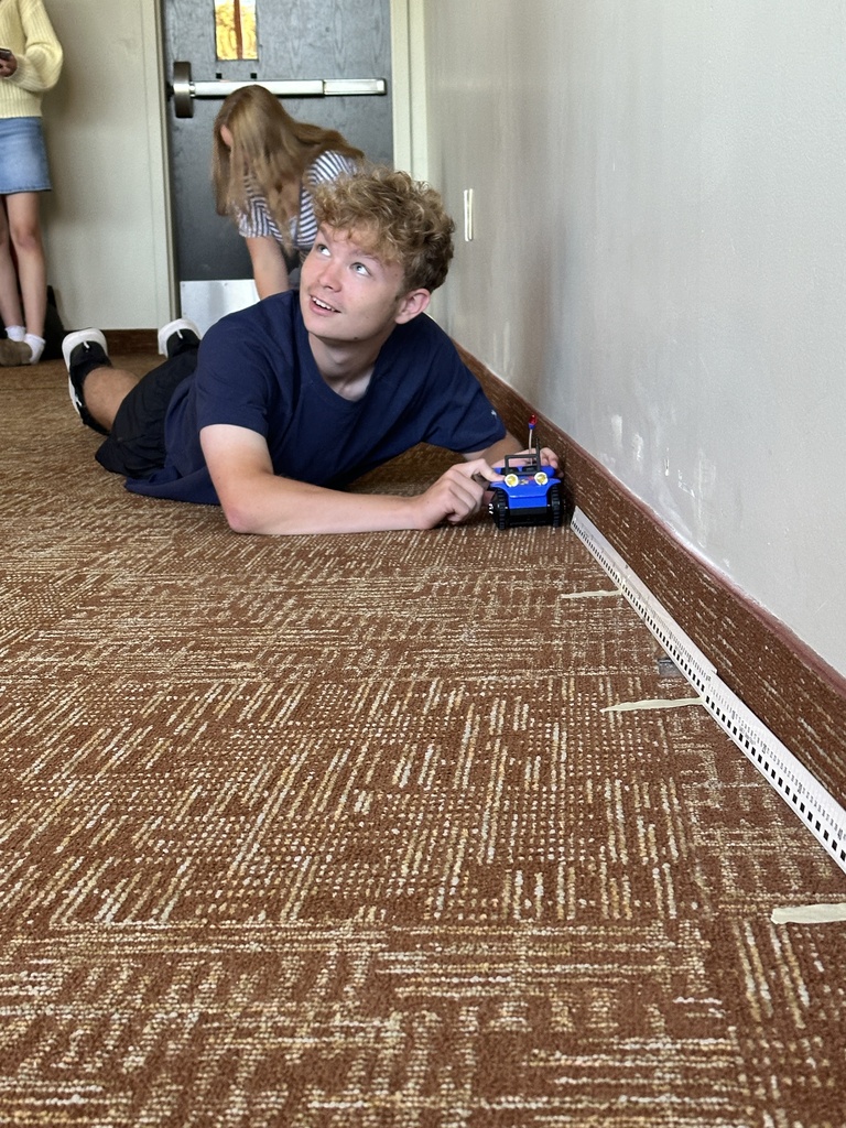 student laying on the floor with a battery powered car
