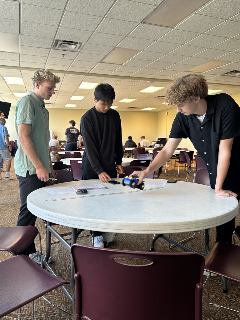 students running an experiment with a battery powered car