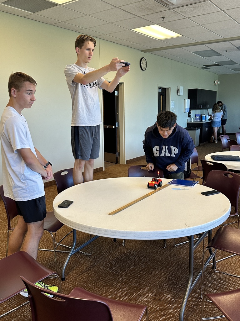 students running an experiment with a battery powered car