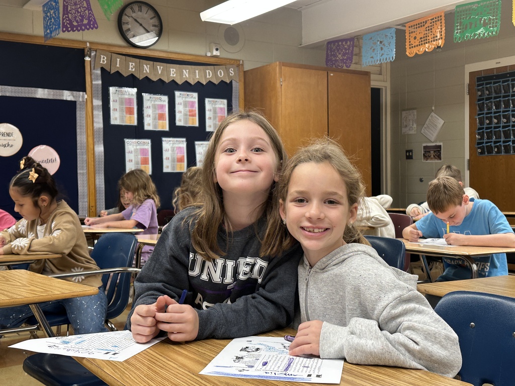 two girls sitting at a desk doing a word search
