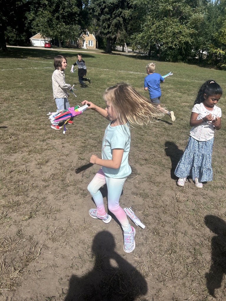 1st grade students playing with their handmade windsocks outside