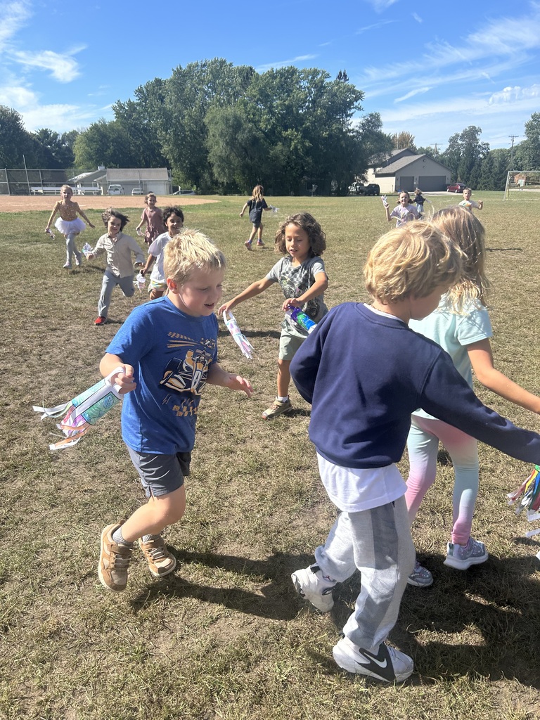 1st grade students playing with their handmade windsocks outside
