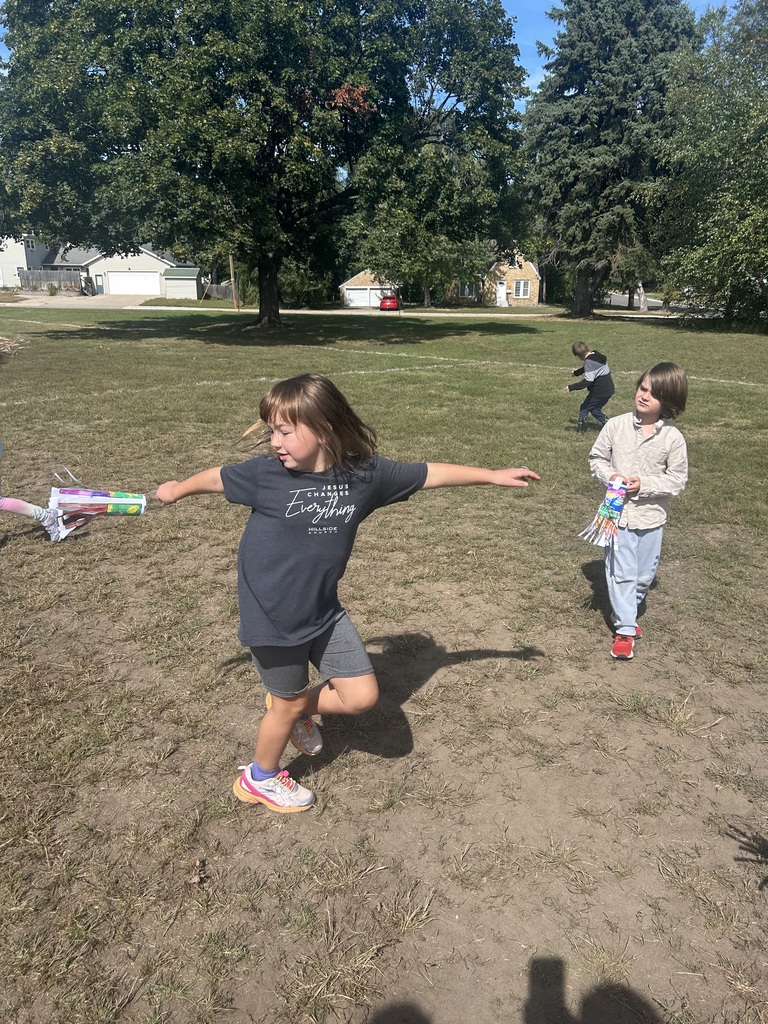 1st grade students playing with their handmade windsocks outside