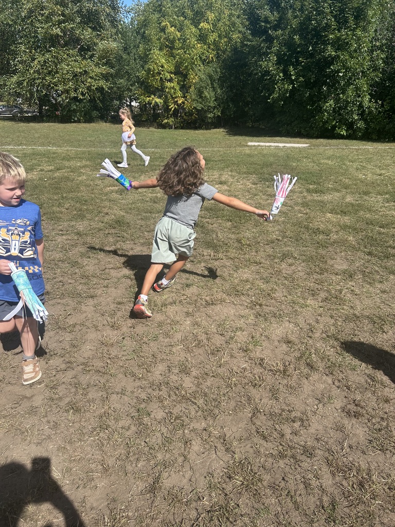 1st grade students playing with their handmade windsocks outside