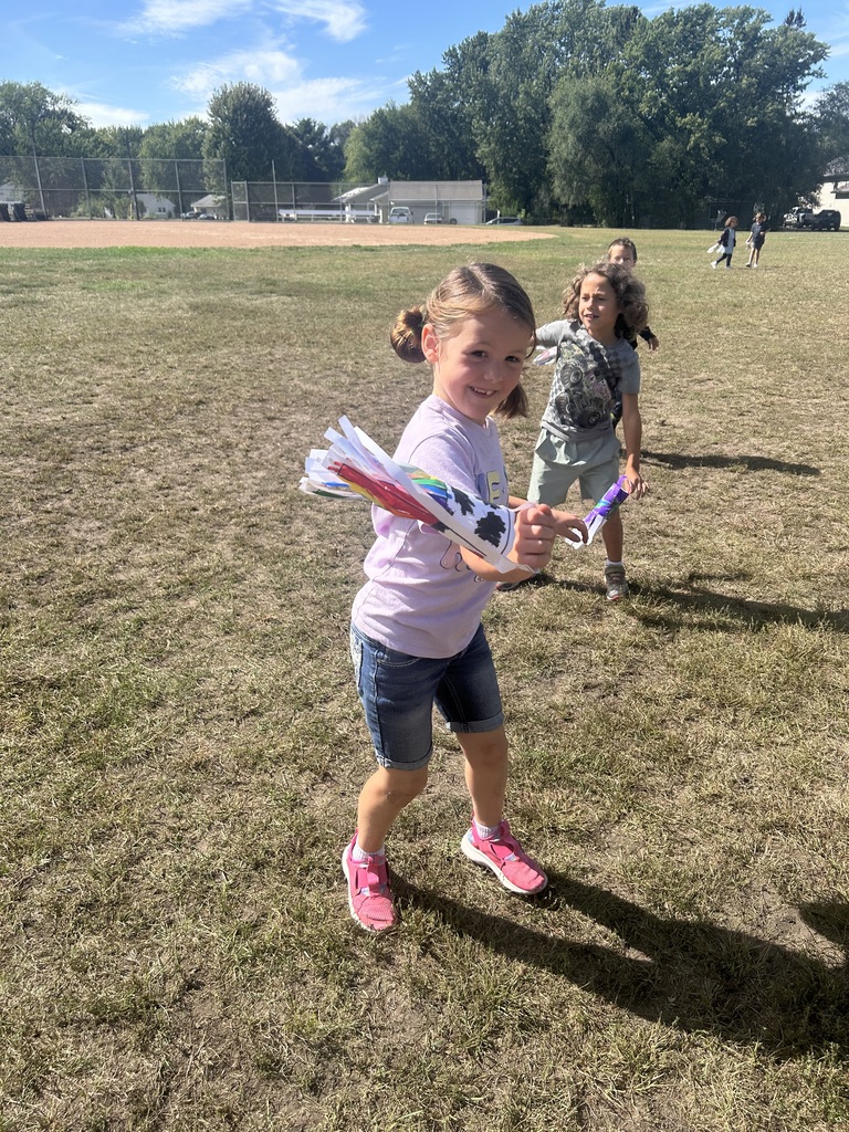 1st grade students playing with their handmade windsocks outside