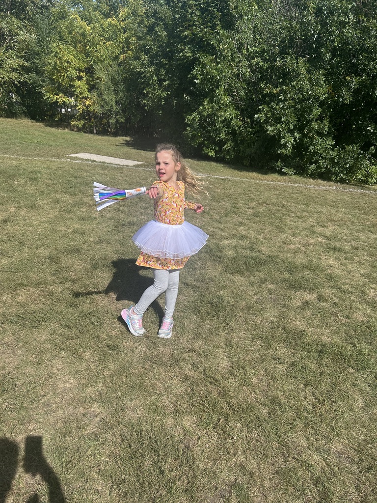 1st grade students playing with their handmade windsocks outside