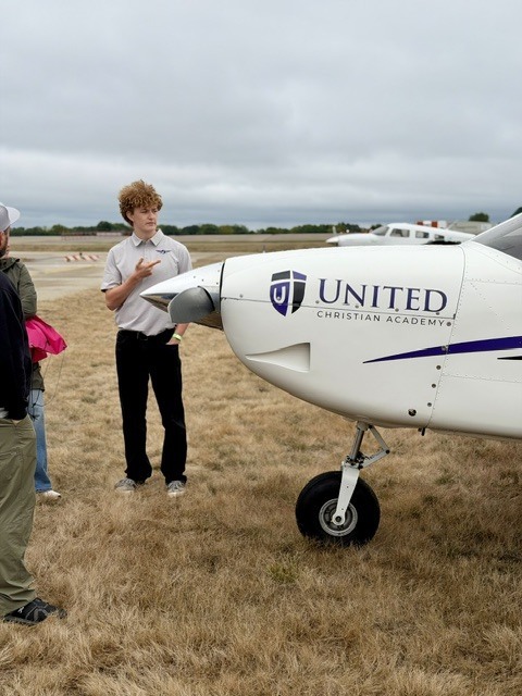 Man standing next to an airplane pointing at it