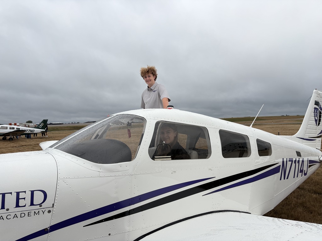 girl sitting inside an airplane, boy standing on the wing