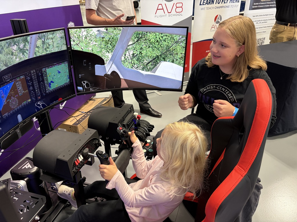 older girl teaching a younger girl to use the flight simulator