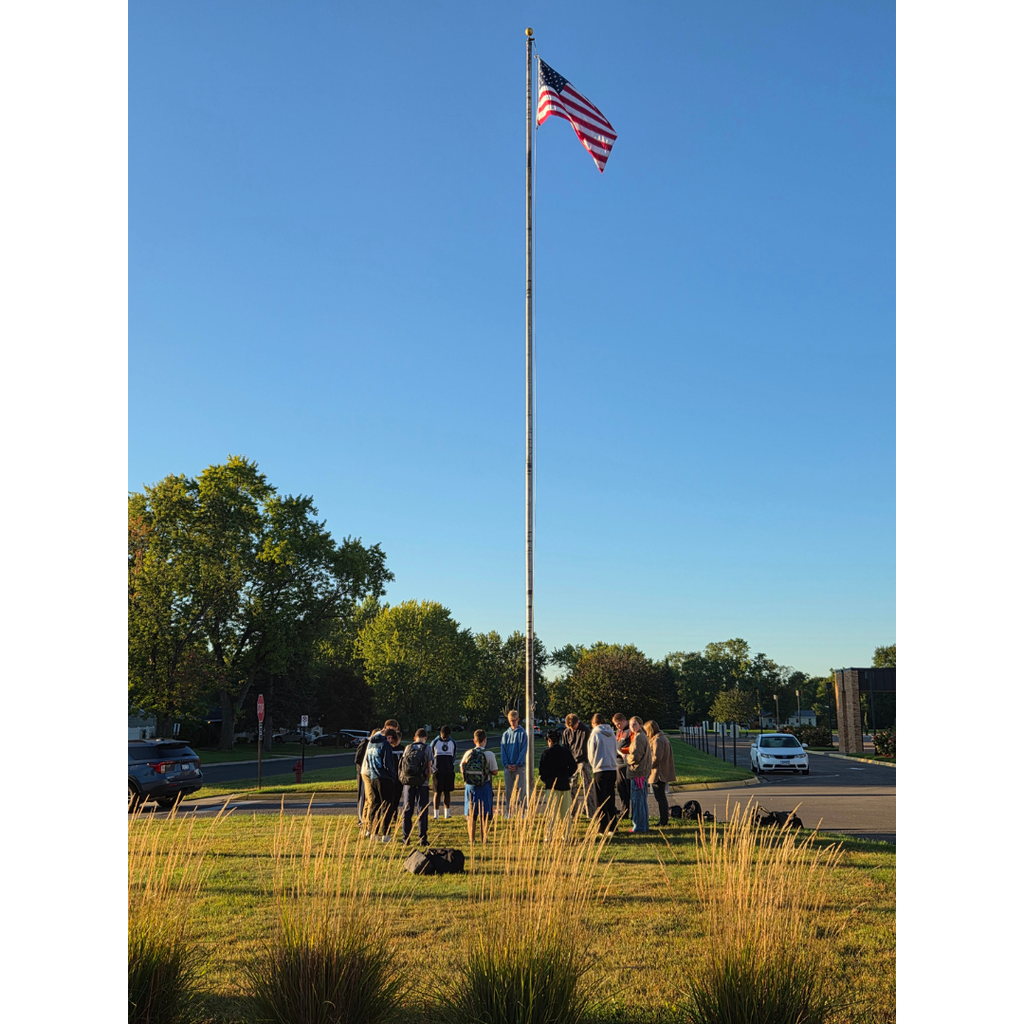 students gathered around a flag pole to pray