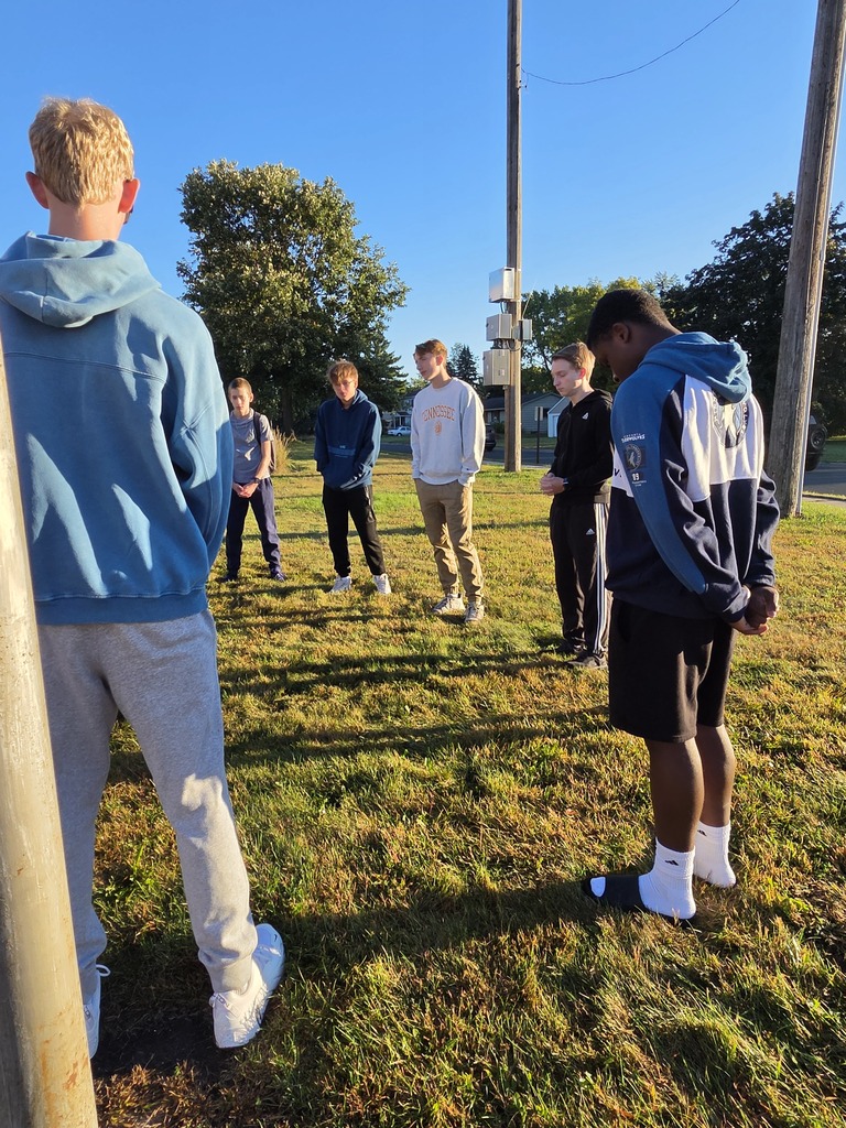 students gathered around a flag pole to pray