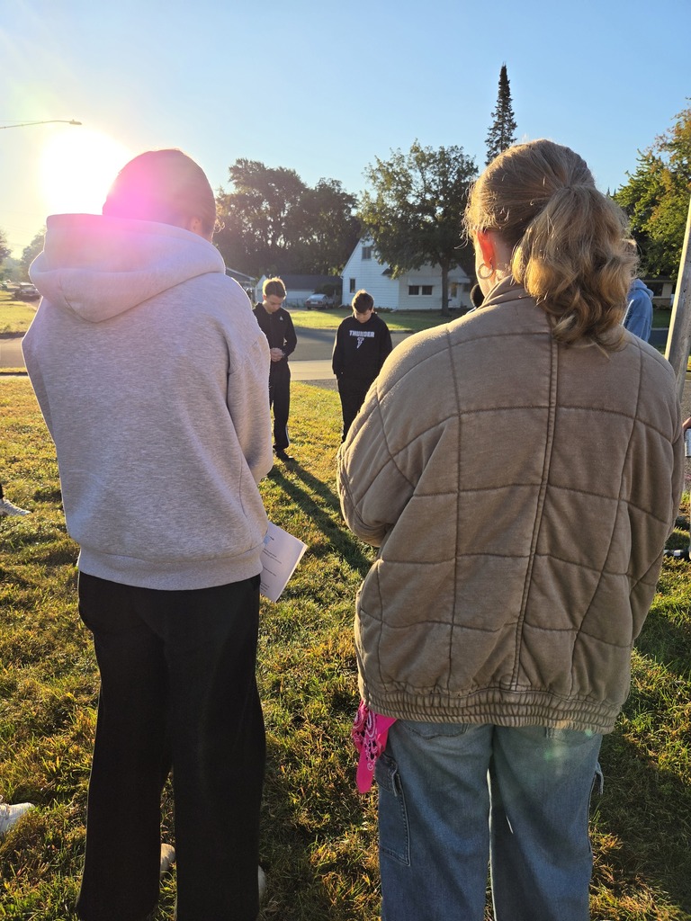 students gathered around a flag pole to pray