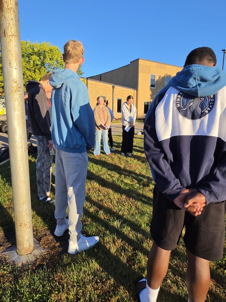 students gathered around a flag pole to pray