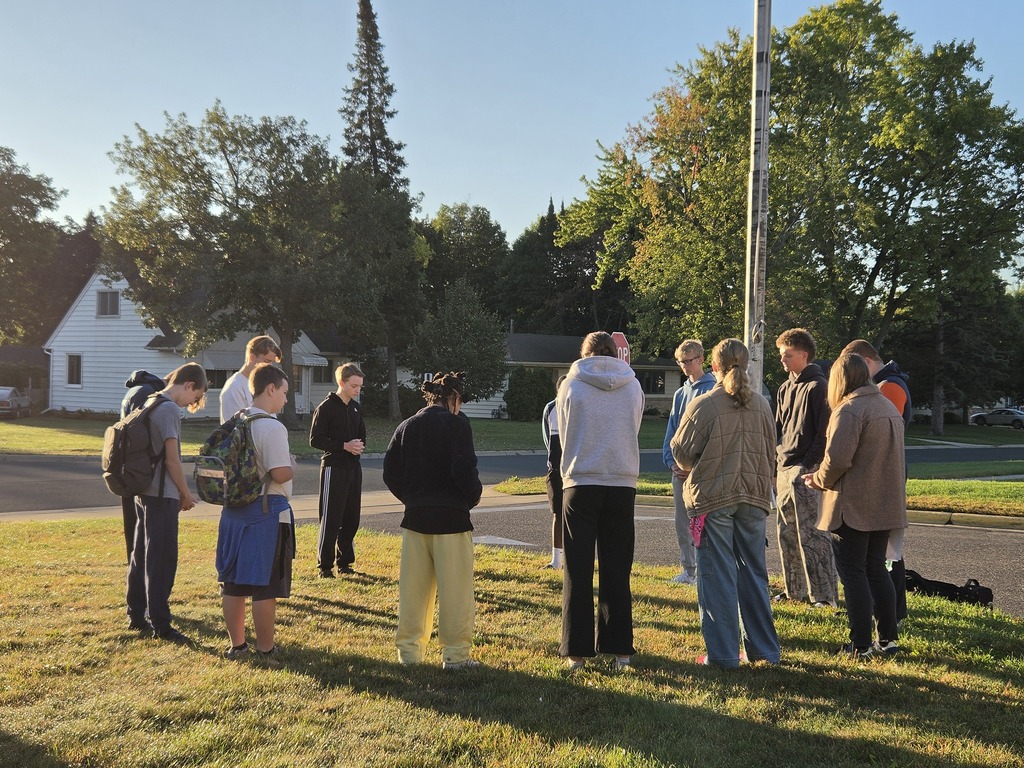 students gathered around a flag pole to pray