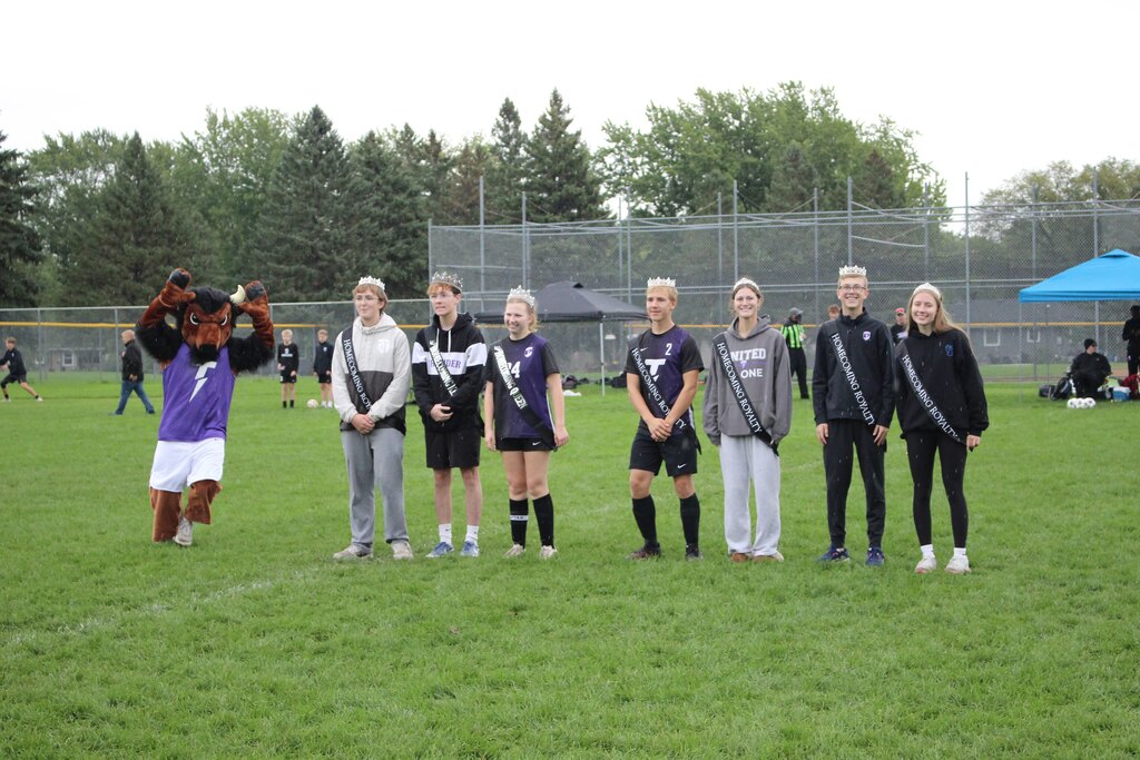 students in the homecoming court standing on the soccer field
