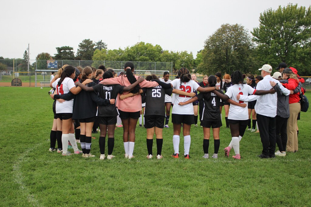 soccer players from two teams huddled together praying