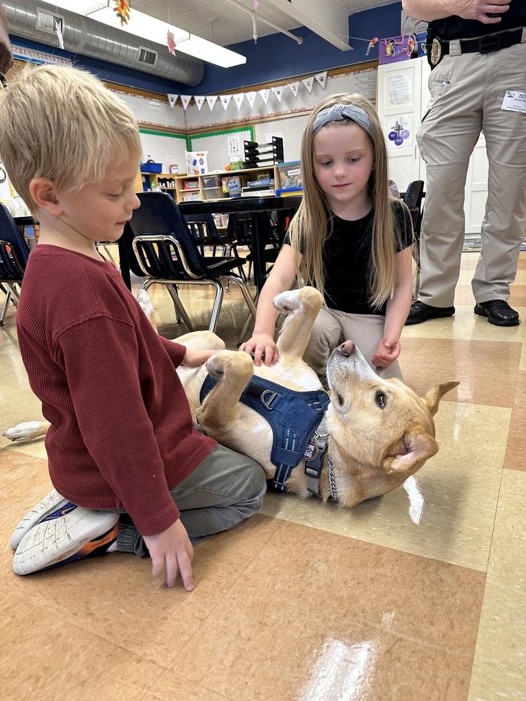 students sitting on the classroom floor petting a dog