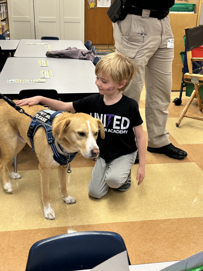 students sitting on the classroom floor petting a dog