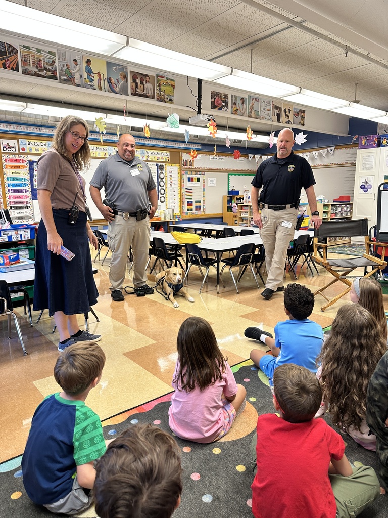 police officers and their dog standing in front of a group of kindergarteners