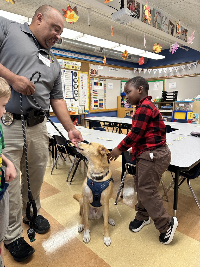 students sitting on the classroom floor petting a dog