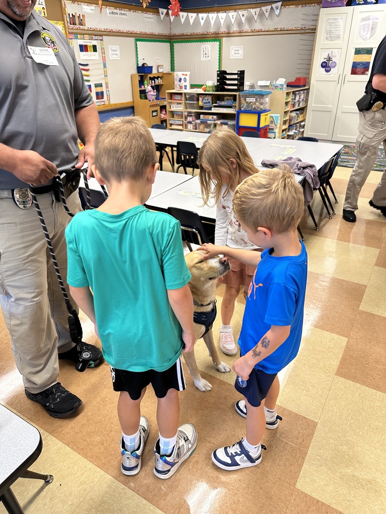 students sitting on the classroom floor petting a dog