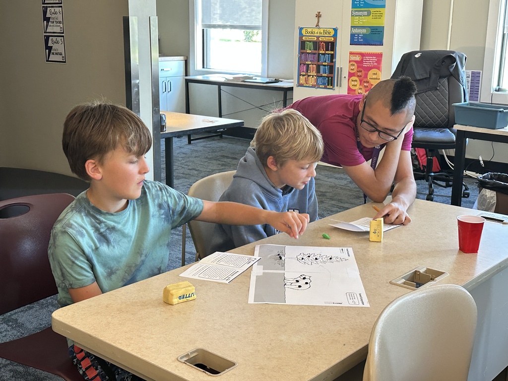 teacher leaning over a students desk to help with their work