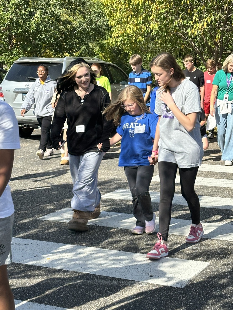 three students holding hands while walking