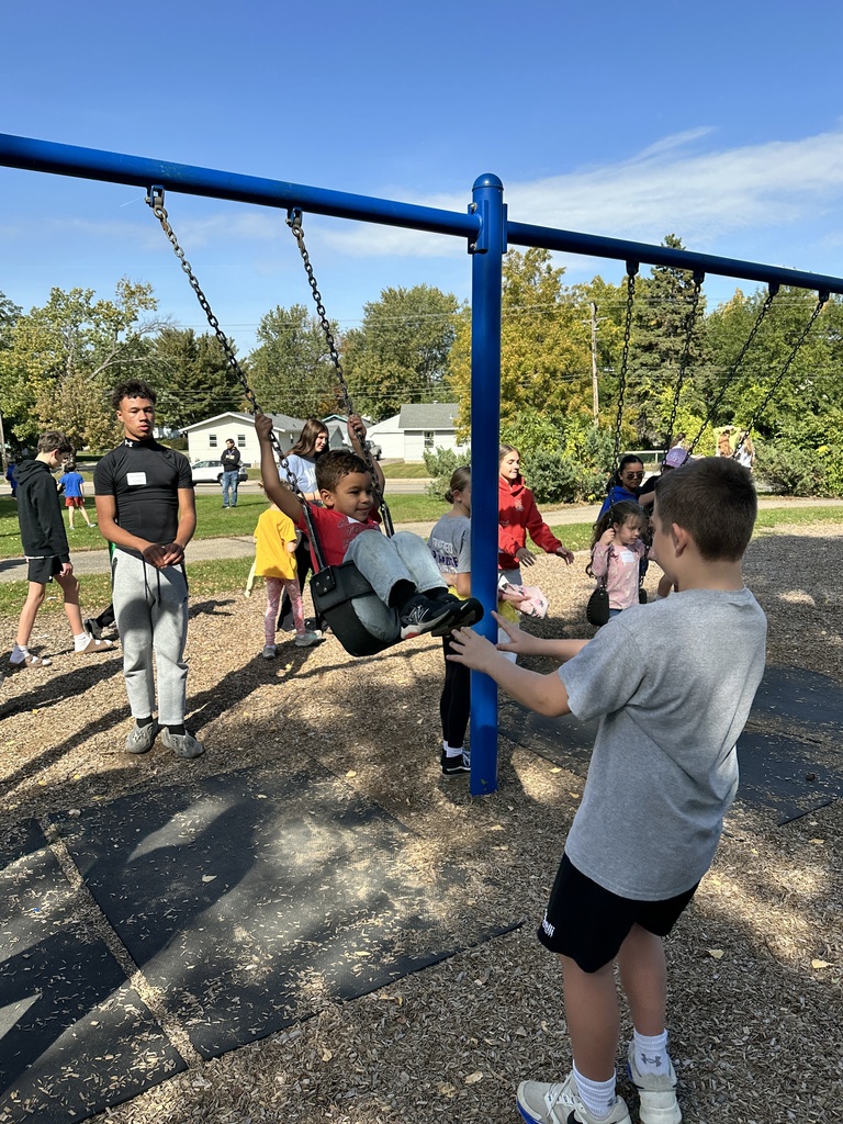 older students pushing younger students on the swings